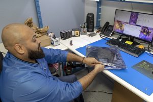 An employee packaging electronic components on a PC desk at AGS Devices.